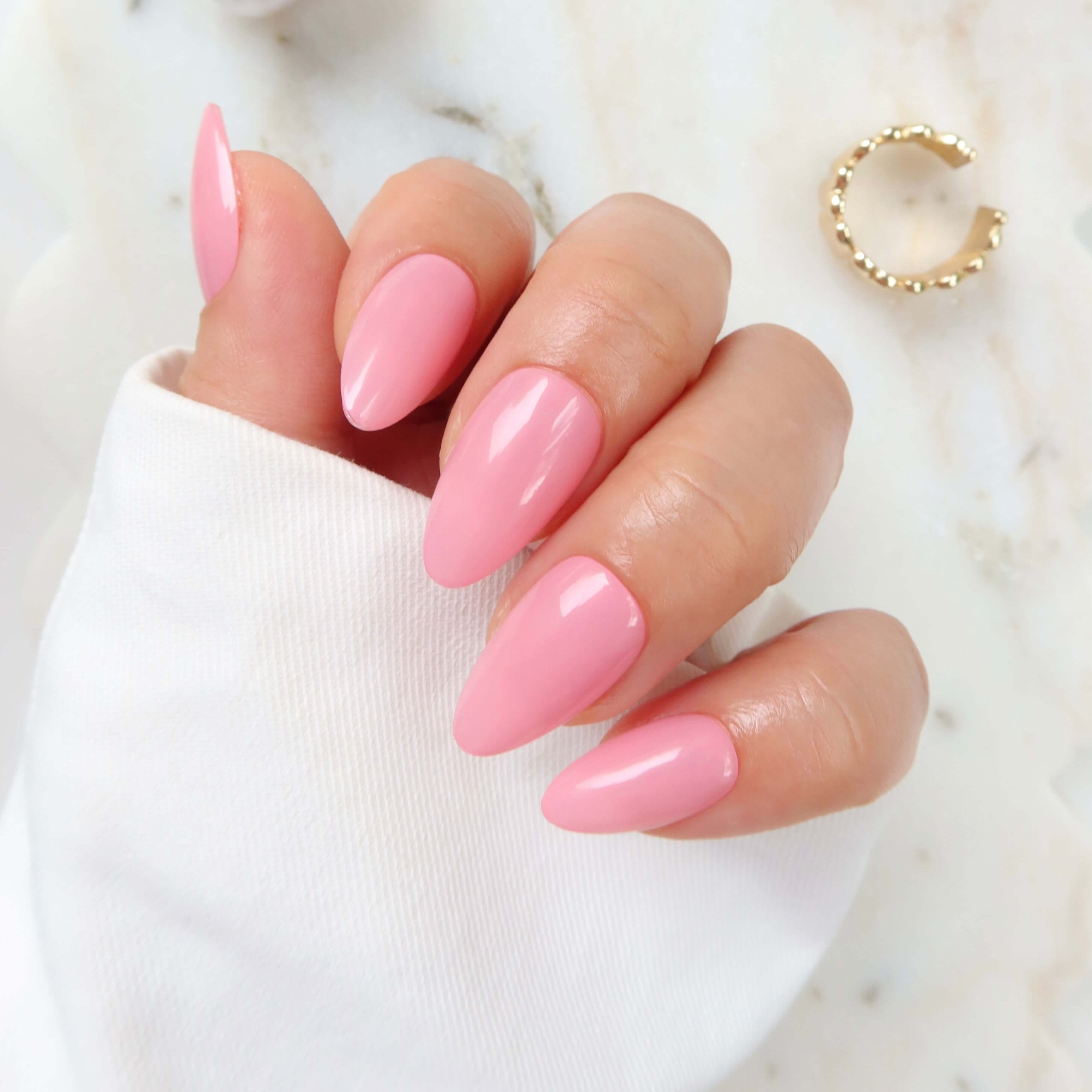 high quality thick press on nails. barbie pink nails. salon grade press on nails New Zealand Cotton candy pink nails with a glossy finish, resting on a marble surface next to gold jewelry.