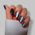 Black and silver cateye press-on nails displayed on a hand with a white sweater cuff.
