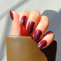 red wine soft gel polish. red wine press on nails. red wine nails short oval short almondWaiheke Merlot nail polish applied on well-groomed nails, showcasing a deep burgundy color with a glossy finish.